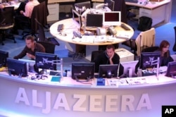 FILE - Al Jazeera English Channel staff prepare for the broadcast in Doha news room in Qatar.