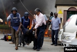 Rescuers and journalists evacuate an injured man from the scene where explosions and gunshots were heard at the Dusit hotel compound, in Nairobi, Kenya, Jan. 15, 2019.