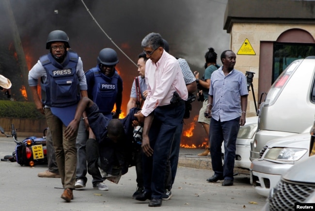 Rescuers and journalists evacuate an injured man from the scene where explosions and gunshots were heard at the Dusit hotel compound, in Nairobi, Kenya, Jan. 15, 2019.