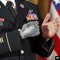 With his prosthetic hand, U.S. Army Sergeant First Class Leroy Arthur Petry applauds fellow soldiers during a ceremony in which he was presented with the Medal of Honor by U.S. President Barack Obama at the White House, July 12, 2011