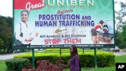 FILE - An unidentified student at Benin University walks past a billboard encouraging young women to fight against prostitution and human trafficking, on the university campus in Benin City, Nigeria on Sept. 9, 2006.