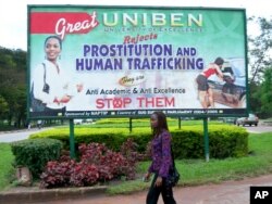 FILE - An unidentified student at Benin University walks past a billboard encouraging young women to fight against prostitution and human trafficking, on the university campus in Benin City, Nigeria, Sept. 9, 2006.