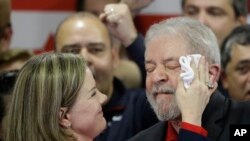 FILE - Worker's Party president, Sen. Gleisi Hoffmann, wipes sweat from the face of former Brazilian President Luiz Inacio Lula da Silva at the end of a brief speech he delivered to media and supporters at the party's headquarters in Sao Paulo, Brazil.