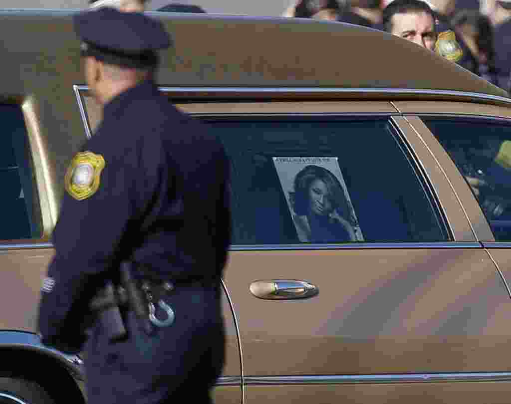 Seorang polisi Newark menyaksikan mobil jenazah Whitney Houston tiba di Gereja New Hope Baptist, New Jersey, 18 Februari 2012 (REUTERS).