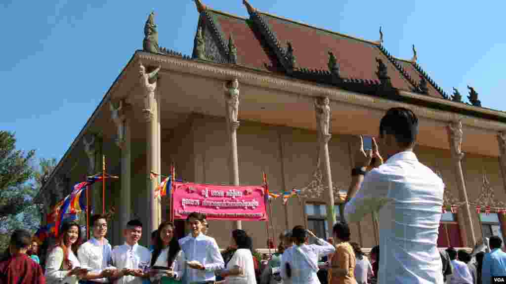 អ្នកកាន់ពុទ្ធសាសនាវ័យក្មេងមួយក្រុមថតរូបជុំគ្នានិងជិតព្រះវិហារ។ (ចាប ចិត្រា/VOA)