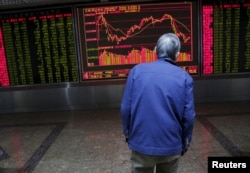 An investor watches an electronic board showing stock information on the first trading day after the week-long Lunar New Year holiday at a brokerage house in Beijing, China, Feb. 15, 2016.