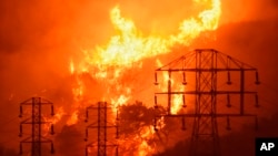 FILE - Flames burn near power lines in Sycamore Canyon near West Mountain Drive in Montecito, Calif., Dec. 16, 2017. The nation's largest utility, on Feb. 6, 2019, promised to overhaul its wildfire-prevention measures in response to its role in starting s