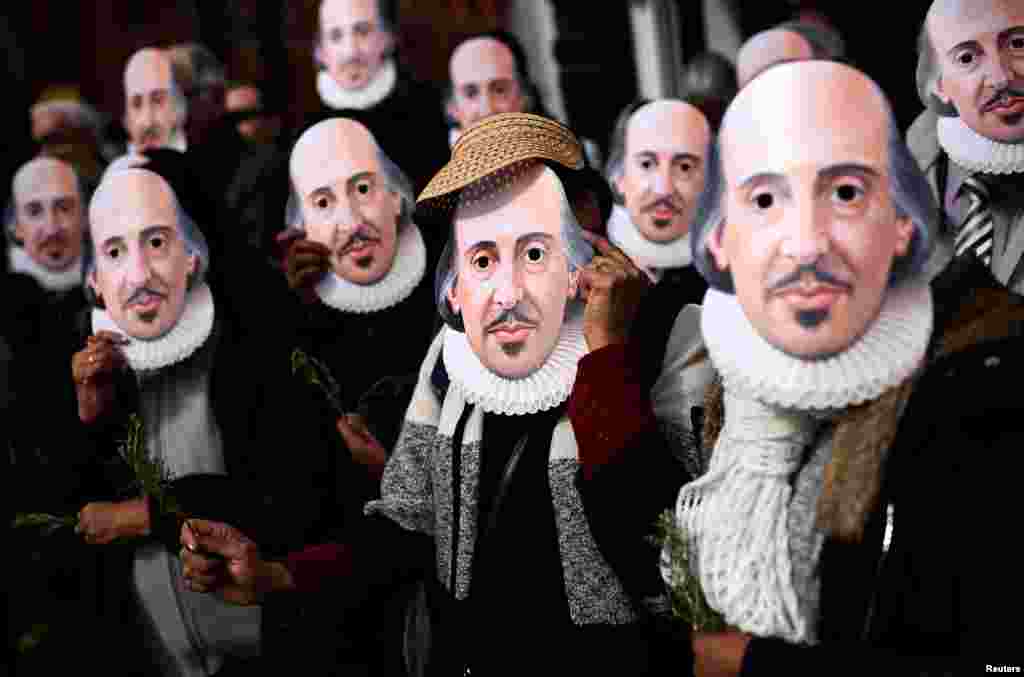 People hold up face masks with William Shakespeare&#39;s portrait during celebrations to mark the 400th anniversary of the playwright&#39;s death in the city of his birth, Stratford-Upon-Avon, Britain, April 23, 2016.