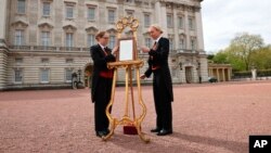 Como parte del protocolo real, personal del Palacio de Buckingham coloca el anuncio oficial de la llegada a este mundo del tercer hijo de la familia real.