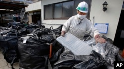 Radioaktiv chiqindilarni yig'ayotgan ishchi, Fukushima, Yaponiya