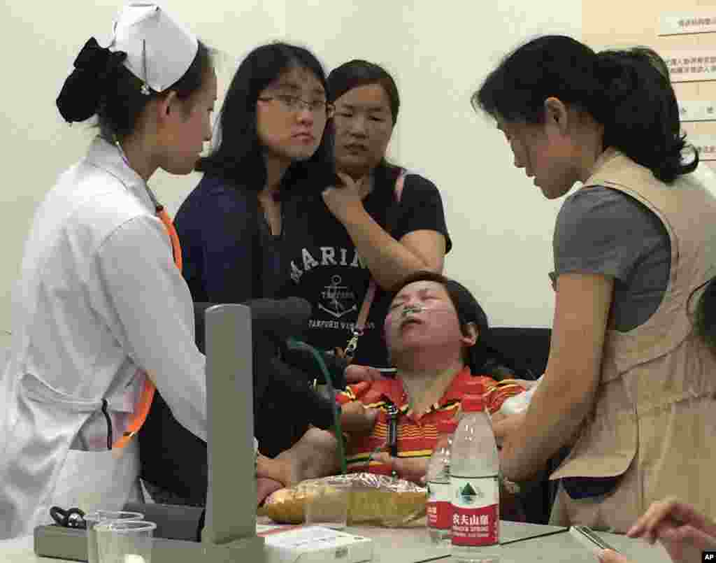A relative of Shanghai passengers on board a cruise ship that capsized in central China, is attended to by a medical worker as she waits for answers at a government office in Shanghai, China, June 2, 2015.