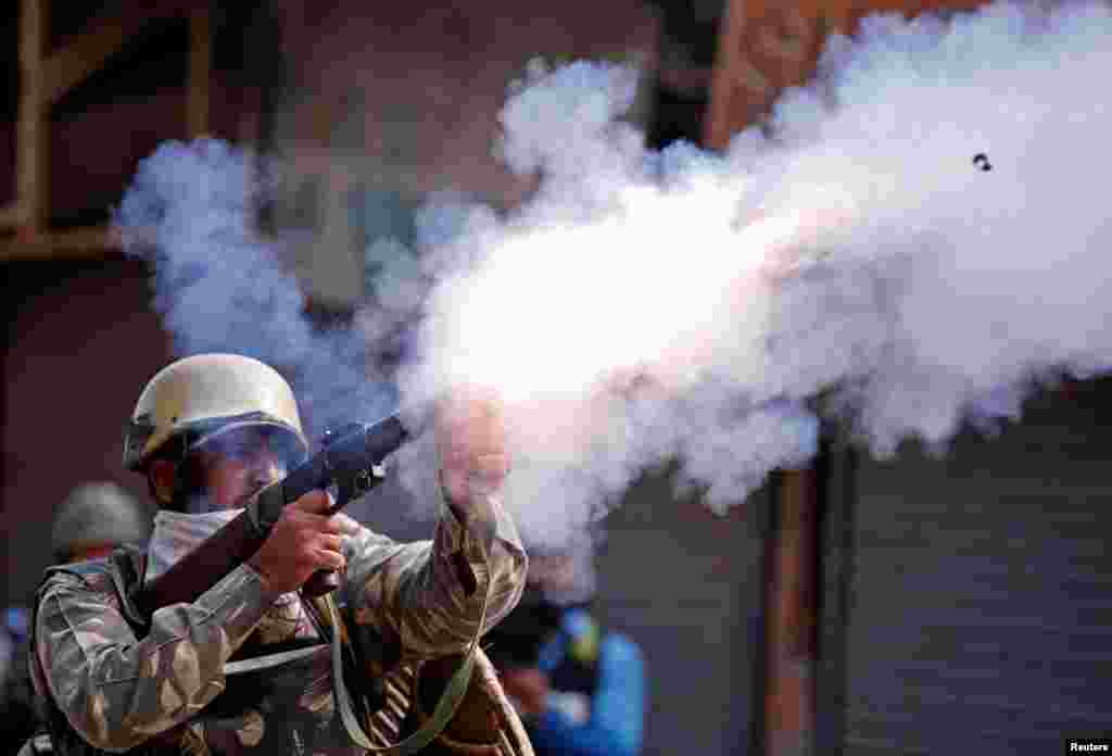 An Indian policeman fires a teargas shell towards demonstrators during a protest against the recent killings in Kashmir, in Srinagar.