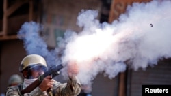 An Indian policeman fires a teargas shell towards demonstrators during a protest against the recent killings in Kashmir, in Srinagar, Sept. 13, 2016.