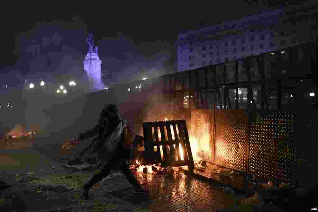 A woman throws a bottle to riot police agents outside the National Congress in Buenos Aires after senators rejected the bill to legalize abortion.