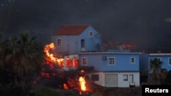 Lava dari gunung berapi Cumbre Vieja tampak membakar beberapa rumah di Pulau Canary, Kepulauan La Palma, Spanyol, pada 19 Oktober 2021. (Foto: Reuters/Susana Vera)