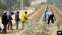 FILE - Construction workers rake gravel on railroad tracks in Thanalaeng, Laos, Feb. 13, 2008.
