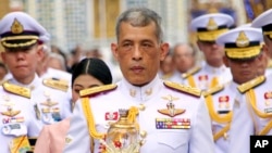 FILE - Thai King Maha Vajiralongkorn, center, holds a candle light during a ceremony at Emerald Buddha temple, in Bangkok, Thailand, May 29, 2018.