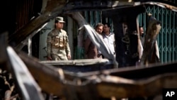 Afghan Army soldier by the wreckage of a destroyed car after a suicide car bomber attacked a NATO convoy in Kabul, May 16, 2013.
