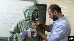 Imágen de un video de un voluntario ajustando su traje contra gases neurotóxicos en Siria.