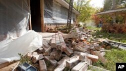 FILE - Chad Devereaux works to clear up bricks that fell from three sides of his in-laws' home in Sparks, Okla., after two earthquakes hit the area in less than 24 hours, April 6, 2011. 