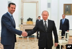 FILE - Russian President Vladimir Putin, center, shakes hand with Syrian President Bashar Assad as Russian Foreign Minister Sergey Lavrov, right, looks on in the Kremlin in Moscow,Oct. 20, 2015.