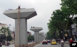 FILE - Motorists pass by a stretch of a metro railway project being constructed in Hanoi, Vietnam.