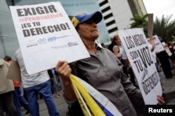 A woman holds placards during a rally to commemorate World Press Freedom Day in Caracas, Venezuela, May 3, 2016. The placards read, "Demanding free press is your right," left, and "The media are your voice. Defend them."