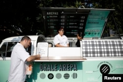 FILE - Venezuelan chef Jorge Udelman, left, 34, prepares to serve Venezuelan food on his food truck called "Orale Arepa," at a parking lot in Mexico City, March 30, 2014.