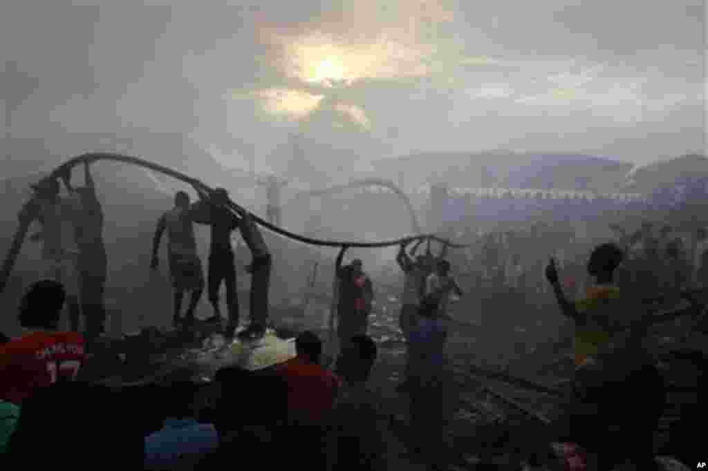 People gather at the site of a Dana Airlines plane crash in Lagos, Nigeria, Sunday, June 3, 2012. Firefighters pulled at least one body from a building that was damaged by the crash and searched for survivors as several charred corpses could be seen in t