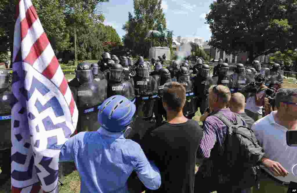 White nationalist demonstrators hold their ground against Virginia State Police as police fire tear gas rounds in Lee Park in Charlottesville, Va., Aug. 12, 2017.