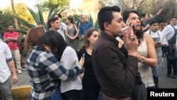 People stand on the street after an earthquake shook buildings in Mexico City, Feb. 16, 2018. 