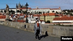 A woman wearing a face mask walks across the medieval Charles Bridge, as the Czech government shut sports, culture and social venues for two weeks to slow down the spread of the coronavirus disease (COVID-19), in Prague, Czech Republic, October 12.