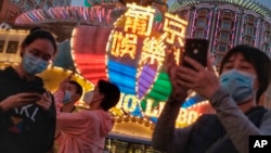 In this Jan, 23, 2020, photo released by Initium Media, tourists wearing masks, take photographs outside the Casino Lisboa in Macao, China. (Choi Chi Chio/Initium Media via AP)