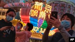 In this Jan, 23, 2020, photo released by Initium Media, tourists wearing masks, take photographs outside the Casino Lisboa in Macao, China. (Choi Chi Chio/Initium Media via AP)