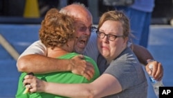Том Саливан во прегратка на семејството. Неговиот син бил во киното за време на нападот.