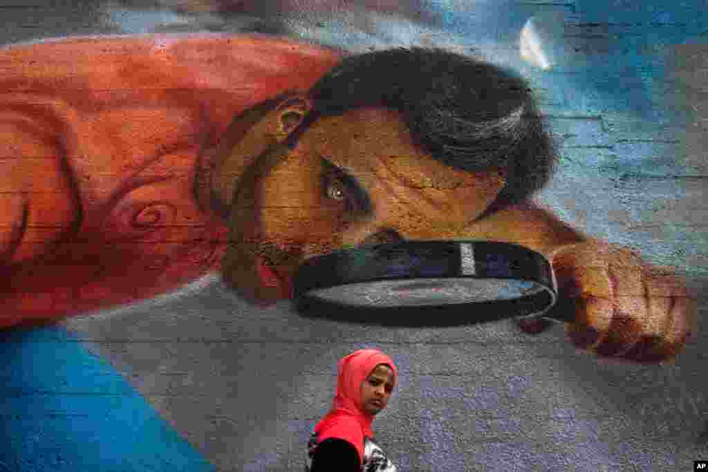 Seorang wanita melintasi tembok berhias seni graffiti di Beirut, Lebanon.