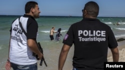 FILE - Tourist police officers patrol at the beach in Sousse, Tunisia, July 1, 2015. 
