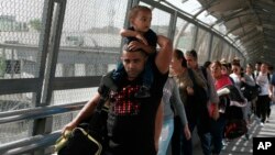 FILE - In this April 29, 2019, photo, Cuban migrants are escorted by Mexican immigration officials in Ciudad Juarez, Mexico, as they cross the Paso del Norte International bridge to be processed as asylum seekers on the U.S. side of the border.