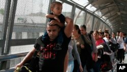 FILE - In this April 29, 2019, photo, Cuban migrants are escorted by Mexican immigration officials in Ciudad Juarez, Mexico, as they cross the Paso del Norte International bridge to be processed as asylum seekers on the U.S. side of the border.