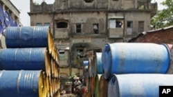 FILE - A laborer works amid oil containers at a wholesale fuel market in Kolkata, India, April 7, 2011. India is set to paying for Iranian crude oil imports.