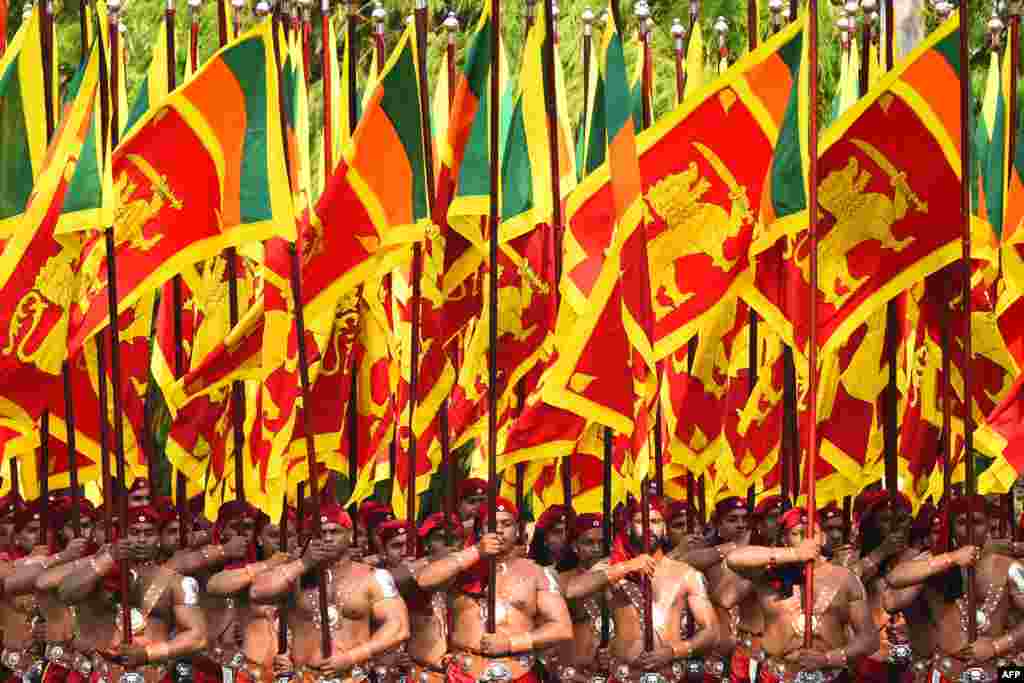 Sri Lankan military personnel march in traditional dress holding national flags during the country&#39;s 72nd Independence Day celebrations in Colombo.