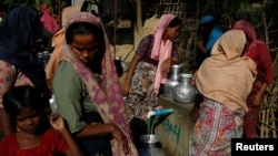 FILE - Rohingya refugee women fill their canisters with water at the Leda refugee camp near Cox's Bazar, Bangladesh, Dec. 16, 2017. 