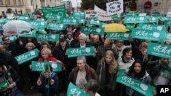 FILE - People take part in a demonstration in support of migrants in front of the Mikolaj Kopernik's statue in Warsaw, Sept. 12, 2015.