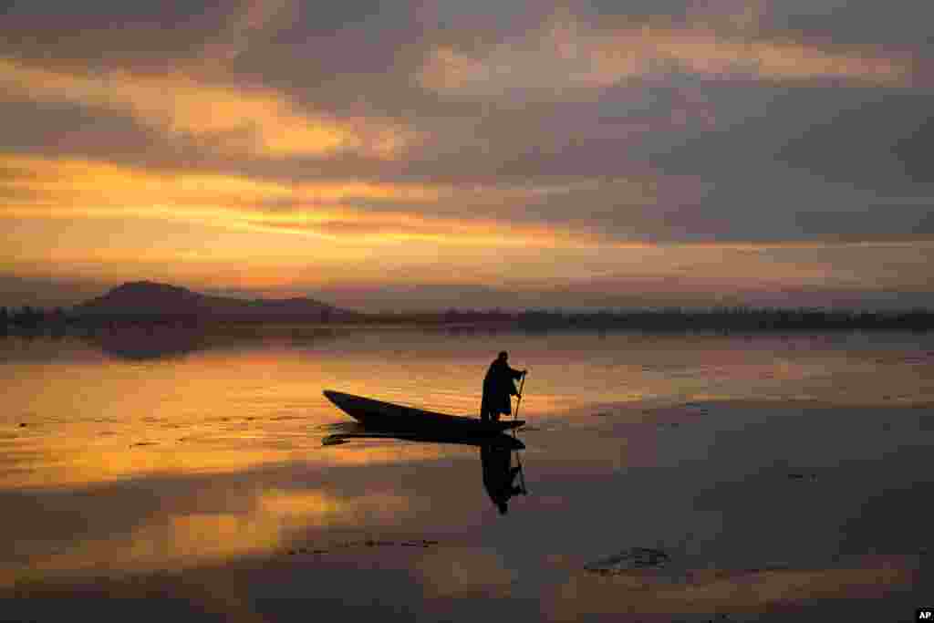 A Kashmiri fisherman rows his Shikara, or traditional boat, during sunset at the Dal Lake in Srinagar, Indian-controlled Kashmir.