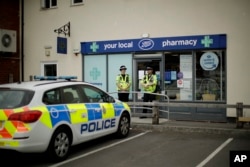 British police officers stand guard outside a branch of the Boots pharmacy in Amesbury, England, July 4, 2018.