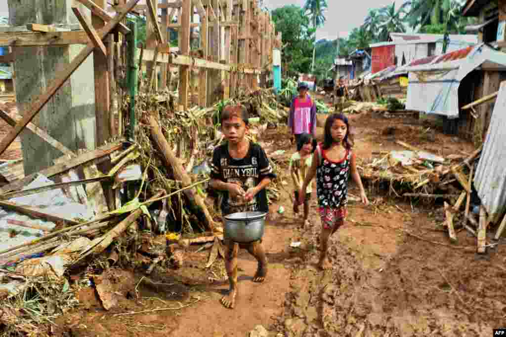 Children walk past debris and damaged houses trees in Barangay San Mateo Borongan in eastern Samar.