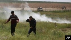 Des manifestants palestiniens se protègent des gaz lacrymogènes tirés par les troupes israéliennes lors d'une manifestation, dans l'est de la ville de Gaza, le 30 mars 2018.