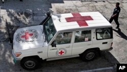 FILE - An Afghan policeman walks past a Red Cross vehicle in Jalalabad, east of Kabul, Afghanistan, May 30, 2013. Suspected Islamist militants reportedly killed six ICRC aid workers and abducted two others Wednesday after ambushing their convoy in northern Jowzjan province. 