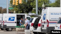 Para petugas kantor pos AS (USPS) menaruh surat-surat dan barang antaran ke dalam sebuah truk pengirim di salah satu lokasi kantor pos di Royal Oak, Michigan, pada 22 Agustus 2020. 