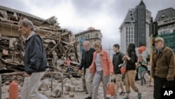 People walk through debris in the aftermath of a 6.3 magnitude earthquake in Christchurch, New Zealand, on February 22, 2011.